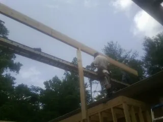 Carpenter setting a ridge beam over a new addition frame — Ice Dam Removal by Roofing Brothers in Ithaca