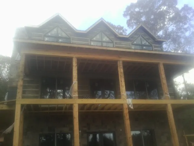 Dormers and porch framing on a large log home under construction — Roof Coating work by our crew in Ithaca