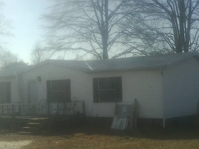 New metal roof on a white painted brick home on a foggy morning in Ithaca