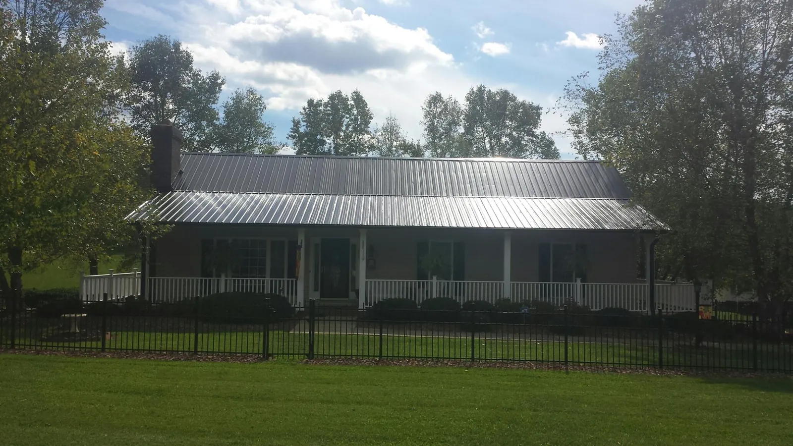 Gray metal roof on a brick ranch with a full width front porch — Gutter Guard Installation work by our crew in Ithaca